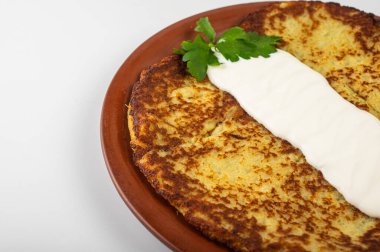 Ekşi kremalı, kahverengi patatesli krep ve kırsal bir tabakta taze maydanoz. Geleneksel Doğu Avrupa yemekleri, gevrek dokular ve nefis ev yapımı yemekler, ev yapımı yemekler.