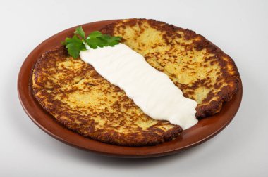 Geleneksel Belarus ya da Ukrayna patates krepleri kızarmış et, sotelenmiş sebze, ekşi krema, peynir, mantar sosu ve ahşap tabakta taze otlar.