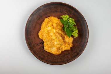 Kırsal bir tabakta taze maydanoz ve marulla süslenmiş altın çıtır tavuk şnitzel. Geleneksel Avrupa mutfağı, ev yapımı konforlu yemekler ve lezzetli kızarmış pirzola.