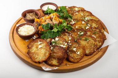 Geleneksel Belarus ya da Ukrayna patates krepleri kızarmış et, sotelenmiş sebze, ekşi krema, peynir, mantar sosu ve ahşap tabakta taze otlar.