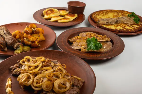 Geleneksel Doğu Avrupa mutfağı kırsal kil tabaklarda servis edilir. Etler, patatesler, krepler, hamur tatlısı ve hafif arka planda ızgara sebzeler dahil olmak üzere çeşitli ev yapımı yemekler