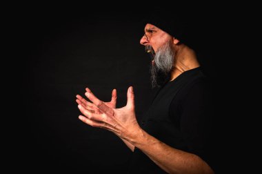 Portre, keskin bakışlı, somurtkan suratlı, gözlüklü, örgü şapkalı ve yana bakan olgun bir adam. Karanlık arka planda güçlü duygularla dizginlenmiş dramatik bir portre..