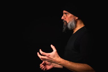 Portre, keskin bakışlı, somurtkan suratlı, gözlüklü, örgü şapkalı ve yana bakan olgun bir adam. Karanlık arka planda güçlü duygularla dizginlenmiş dramatik bir portre..