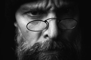 Siyah örgü şapkalı, sakallı ve gözlüklü kendine güvenen olgun bir adamın siyah beyaz portresi. Keskin bir bakış, duygusal gri bir sakal ve siyah bir yelek. Koyu bir arkaplanda zarif bir portre..