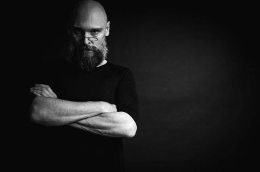 Kısa, kel ve gözlüklü, kendine güvenen olgun bir adamın siyah beyaz portresi. Keskin bir bakış, gri bir sakal ve siyah bir yelek. Koyu bir arka planda zarif, kısıtlı bir portre..