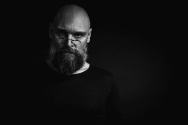 Kısa, kel ve gözlüklü, kendine güvenen olgun bir adamın siyah beyaz portresi. Keskin bir bakış, gri bir sakal ve siyah bir yelek. Koyu bir arka planda zarif, kısıtlı bir portre..