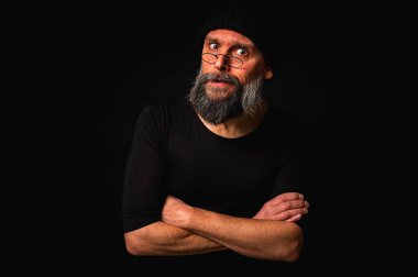 Kollarını önünde kavuşturmuş, örgü şapka ve gözlük takan kendinden emin olgun bir adamın şık portresi. Bakışları, gri sakalı ve siyah yeleği vardı. Karanlık bir arkaplanda zarif, ihtiyatlı bir portre..