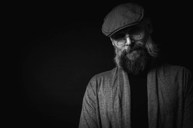 Siyah ve beyaz, siyah arka planda gözlüklü ve şapkalı ciddi sakallı bir adamın Macro portresi. Şık, kendine güvenen ve gizemli bir ifadeyle etkileyici bir bakış.