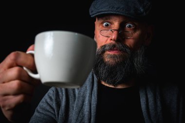 Şık şapkalı ve gözlüklü olgun sakallı bir adam gizemli bir gülümsemeyle bir fincan kahve sunuyor. Dramatik ışıklandırma ve karanlık arkaplan klasik mod yaratır