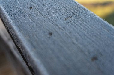 Güneş ışığı ve yumuşak arka plan bulanıklığı ile sabah çiğ ile kaplı ahşap korkuluklara yakın çekim. Doğa, doku, tazelik ve odaklanma temaları için mükemmel bir görüntü.