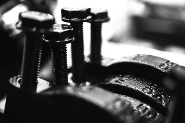 Metal otomobil motor parçaları ve mekanik detaylardan oluşan siyah-beyaz yakın çekim endüstriyel ekipmanları, hassas mühendisliği ve mekanik süreçleri sembolize ediyor, seçici odaklanma