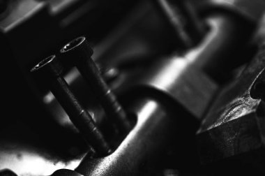 Metal otomobil motor parçaları ve mekanik detaylardan oluşan siyah-beyaz yakın çekim endüstriyel ekipmanları, hassas mühendisliği ve mekanik süreçleri sembolize ediyor, seçici odaklanma