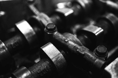 Metal otomobil motor parçaları ve mekanik detaylardan oluşan siyah-beyaz yakın çekim endüstriyel ekipmanları, hassas mühendisliği ve mekanik süreçleri sembolize ediyor, seçici odaklanma