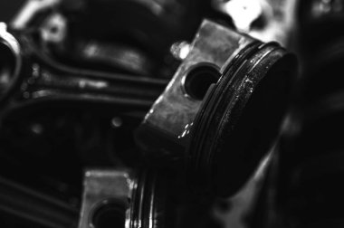 Metal otomobil motor parçaları ve mekanik detaylardan oluşan siyah-beyaz yakın çekim endüstriyel ekipmanları, hassas mühendisliği ve mekanik süreçleri sembolize ediyor, seçici odaklanma