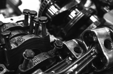 Metal otomobil motor parçaları ve mekanik detaylardan oluşan siyah-beyaz yakın çekim endüstriyel ekipmanları, hassas mühendisliği ve mekanik süreçleri sembolize ediyor, seçici odaklanma