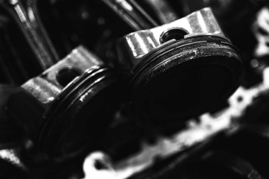Metal otomobil motor parçaları ve mekanik detaylardan oluşan siyah-beyaz yakın çekim endüstriyel ekipmanları, hassas mühendisliği ve mekanik süreçleri sembolize ediyor, seçici odaklanma