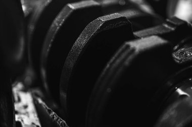 Metal otomobil motor parçaları ve mekanik detaylardan oluşan siyah-beyaz yakın çekim endüstriyel ekipmanları, hassas mühendisliği ve mekanik süreçleri sembolize ediyor, seçici odaklanma