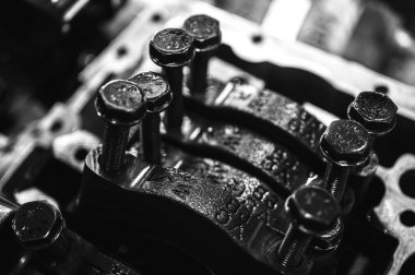 Metal otomobil motor parçaları ve mekanik detaylardan oluşan siyah-beyaz yakın çekim endüstriyel ekipmanları, hassas mühendisliği ve mekanik süreçleri sembolize ediyor, seçici odaklanma