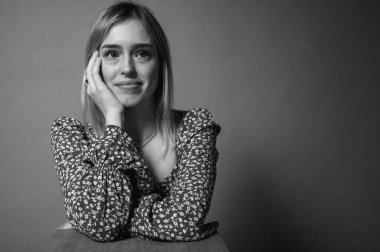 Siyah ve beyaz portre, çiçek desenli elbiseli, elleri havada, arka planda hareketler yapan, yana bakan genç, duygusal sarışın kadın. Parlak yüz ifadesi ve neşeli enerji.