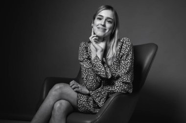 Siyah ve beyaz portre, çiçek desenli elbiseli, elleri havada, arka planda hareketler yapan, yana bakan genç, duygusal sarışın kadın. Parlak yüz ifadesi ve neşeli enerji.