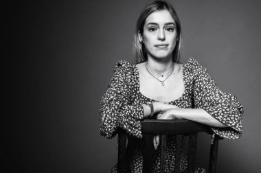 Siyah ve beyaz portre, çiçek desenli elbiseli, elleri havada, arka planda hareketler yapan, yana bakan genç, duygusal sarışın kadın. Parlak yüz ifadesi ve neşeli enerji.