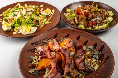 Geleneksel Doğu Avrupa mutfağı kırsal kil tabaklarda servis edilir. Et, patates, krep, hamur köftesi ve ızgara sebzeler dahil olmak üzere çeşitli ev yapımı yemekler, kırsal bir arka plan, üst manzara..