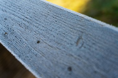 Güneş ışığı ve yumuşak arka plan bulanıklığı ile sabah çiğ ile kaplı ahşap korkuluklara yakın çekim. Doğa, doku, tazelik ve odaklanma temaları için mükemmel bir görüntü..