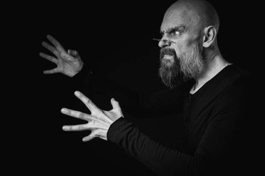 Uzun gri sakallı ve gözlüklü komik bir kel adamın siyah beyaz portresi komik bir surat yapıyor. Eksantriklik, mizah ve anlamlı kişilik kavramı.