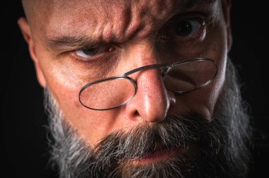 Uzun gri sakallı ve gözlüklü tuhaf kel bir adamın komik yakın plan portresi, aptal bir surat yapıyor. Eksantriklik, mizah ve anlamlı kişilik kavramı.