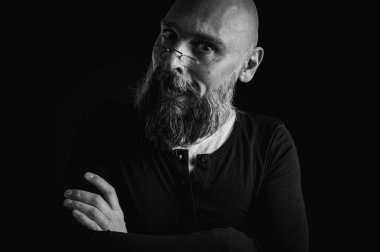 Uzun gri sakallı ve gözlüklü komik bir kel adamın siyah beyaz portresi komik bir surat yapıyor. Eksantriklik, mizah ve anlamlı kişilik kavramı.