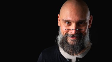 Uzun gri sakallı ve gözlüklü şık kel bir adamın duygusal yakın çekimi ciddi bir bakış yaratıyor. Eksantriklik, mizah ve anlamlı kişilik kavramı.