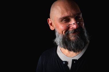 Uzun gri sakallı ve gözlüklü şık kel bir adamın duygusal yakın çekimi ciddi bir bakış yaratıyor. Eksantriklik, mizah ve anlamlı kişilik kavramı.