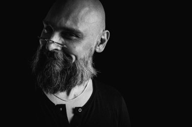 Sakallı bir adamın siyah beyaz portresi sessiz bir jest yapıyor parmakları dudaklarda, duygularda, jestlerde. Gizemli gizli kavramlar. Siyah arkaplanda dramatik ışıklandırma ve ciddiyetle portre..