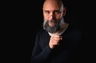 Sakallı adam sessiz hareketler yapıyor. Parmakları dudaklarında. Gizemli gizli konsept. Siyah arkaplanda dramatik ışıklandırma ve ciddiyetle portre