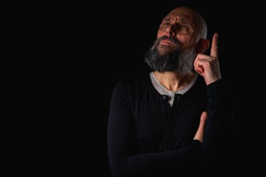 Sakallı ve gözlüklü düşünceli kel adam yukarı bakıyor, tapınağa dokunuyor, derin düşüncelere dalmış, siyah arka planda soyutlanmış. Fikir kavramı, plan, karar verme