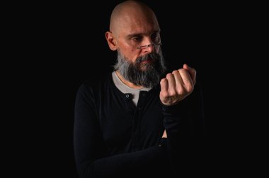 Sakallı ve gözlüklü düşünceli kel adam yukarı bakıyor, tapınağa dokunuyor, derin düşüncelere dalmış, siyah arka planda soyutlanmış. Fikir kavramı, plan, karar verme