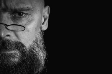 Uzun gri sakallı, gözlüklü, komik suratlı, yarı suratlı tuhaf kel bir adamın komik yakın çekimi. Eksantriklik, mizah ve anlamlı kişilik kavramı.