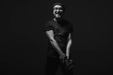 Yukarı bakan kameralı profesyonel erkek fotoğrafçı. Karanlık, sade arka planda siyah beyaz bir stüdyo resmi, yaratıcı bir vizyon, sade bir anahtar.