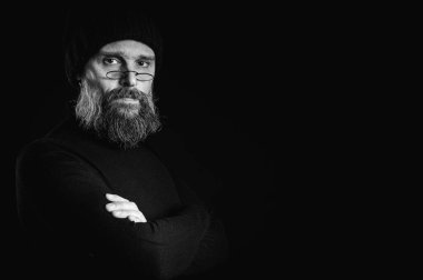 Uzun sakallı, gözlüklü ve bereli bir adamın çarpıcı siyah beyaz portresi. Yoğun, doğrudan bakışlar, bilgelik ve benzersizlik.