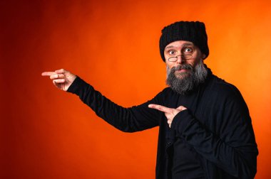 İki eli parlak turuncu arka planda, sakallı ve gözlüklü etkileyici bir adam. Sürpriz, dikkat, yön, tavsiye