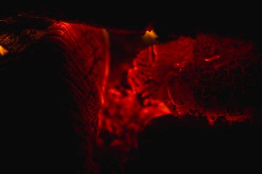 Şöminede yanan odunların samimi arka planı. Parlayan közlere ve sıcak alevlere yakın çekim. Konfor, sıcaklık ve kış kızarıklığı kavramı.