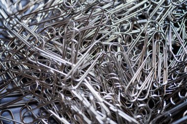 Monokromda parlak metal ataçların soyut yakın çekimi. Organizasyonu, ofis işini, bağlantıyı ve işi simgeler. Şirket, kırtasiye veya minimalist tasarım temaları için mükemmel