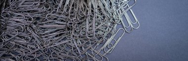 A chaotic yet captivating close-up of numerous metallic paper clips in a monochrome palette, highlighting their intricate shapes and textures. Ideal for office, creativity, and abstract themes