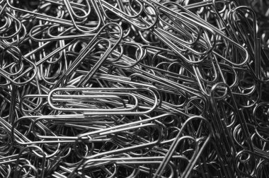 A chaotic yet captivating close-up of numerous metallic paper clips in a monochrome palette, highlighting their intricate shapes and textures. Ideal for office, creativity, and abstract themes