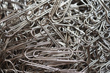 A chaotic yet captivating close-up of numerous metallic paper clips in a monochrome palette, highlighting their intricate shapes and textures. Ideal for office, creativity, and abstract themes