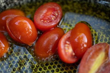 Taze vişneli domatesler tavada zeytinyağı içinde cızırdıyor. Mutfak, sağlıklı beslenme, Akdeniz mutfağı ve blog temaları için mükemmel. Canlı renkler ve lezzetli dokular yakalar.