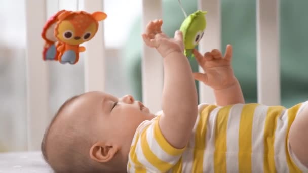 モバイルカルーセルと笑顔を見てベビーベッドで3ヶ月の赤ちゃん 幸せな子供だ 新生児はベビーベッドにいます 子供のためのモバイル — ストック動画