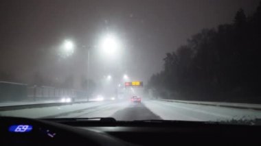 Karlı bir otoyolda gece aşırı araba kullanmak. Arabanın ön camına kar taneleri düşer. Yol tabelasında kötü sürüş koşulları yazıyor.