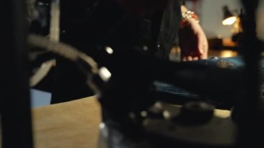 Bir kadın terzi, atölyede eski kot elbiseleri tamir etmeden önce kot pantolon ütülüyor. Küçük aile şirketi, terzilik ve giysi onarımı, el yapımı, terzilik, gelenek