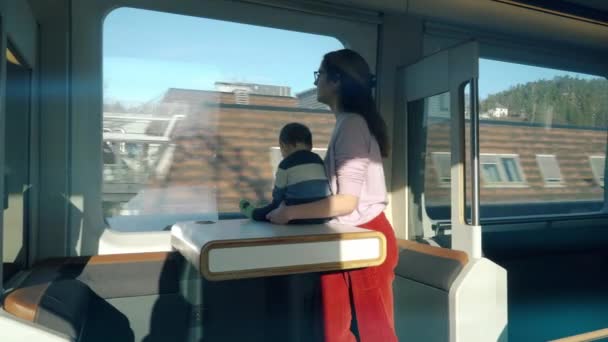 一位年轻的妇女和她的孩子乘坐高速快车 欣赏窗外美丽的风景 探索新的地方 — 图库视频影像